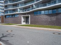 the building has a window above the entrance on this sidewalk near a street in front of the building