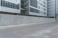 a woman riding a skateboard in an empty area next to buildings and a concrete wall