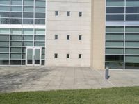 a tall building with some windows near grass and grass bushes in front of it and a parking meter