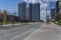 a view of a empty city street next to tall buildings and a street light on a corner