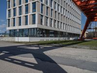 an apartment building next to a parking lot with the shadow of a pedestrian on the road