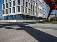 an apartment building next to a parking lot with the shadow of a pedestrian on the road