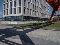 an apartment building next to a parking lot with the shadow of a pedestrian on the road