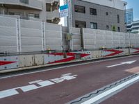 the man is riding his bicycle down the street next to a guard line that has arrows pointing up