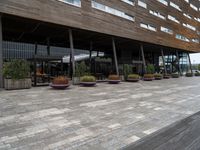 outside building with pots and plants and table benches and tables set out in front of it