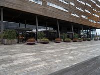 outside building with pots and plants and table benches and tables set out in front of it