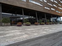 outside building with pots and plants and table benches and tables set out in front of it