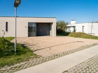 the courtyard area features a cement pavers pathway leading to a building with an open garage and several windows