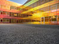 an outside picture of an urban area with orange sky in the background with yellow colored light reflecting off it's windows