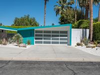 the modern home features a bright turquoise - painted exterior and palm trees, as well as large green shrubs