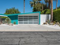 the modern home features a bright turquoise - painted exterior and palm trees, as well as large green shrubs