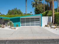 the modern home features a bright turquoise - painted exterior and palm trees, as well as large green shrubs