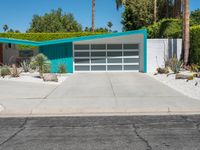 the modern home features a bright turquoise - painted exterior and palm trees, as well as large green shrubs