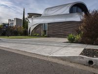 this modern home has a curved facade in architecture style and has concrete steps leading up to the front