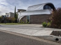 this modern home has a curved facade in architecture style and has concrete steps leading up to the front