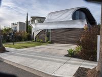 this modern home has a curved facade in architecture style and has concrete steps leading up to the front