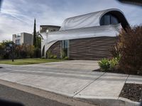 this modern home has a curved facade in architecture style and has concrete steps leading up to the front