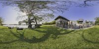 a fish eye image of a home on the grass in a park with trees and water