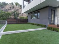 a modern home has grass and plants in the yard by the stairs of the house