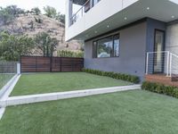 a modern home has grass and plants in the yard by the stairs of the house