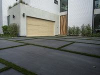 a modern home with concrete pavers and grass on it, there is a large garage