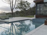 the large pool on the hillside overlooks the view of the valley below it and leads into a modern home's backyard