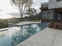 the large pool on the hillside overlooks the view of the valley below it and leads into a modern home's backyard