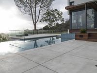 the large pool on the hillside overlooks the view of the valley below it and leads into a modern home's backyard