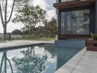 the large pool on the hillside overlooks the view of the valley below it and leads into a modern home's backyard