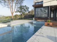 the large pool on the hillside overlooks the view of the valley below it and leads into a modern home's backyard