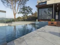 the large pool on the hillside overlooks the view of the valley below it and leads into a modern home's backyard