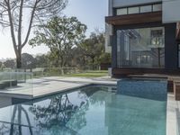 the large pool on the hillside overlooks the view of the valley below it and leads into a modern home's backyard