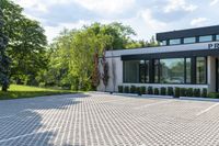 a modern white home with a paved driveway and large windows overlooking the view in a nice landscape