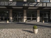 the front entrance to a modern hotel with large glass doors and plants in planters