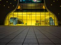 the entrance of a modern hotel lit up by yellow leds at night in the city