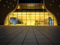 the entrance of a modern hotel lit up by yellow leds at night in the city