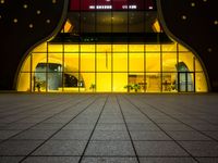 the entrance of a modern hotel lit up by yellow leds at night in the city