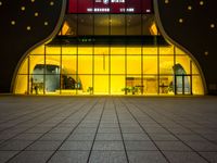 the entrance of a modern hotel lit up by yellow leds at night in the city