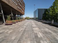 an empty brick walkway leads to an office building and trees in the background for a caption