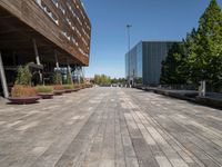 an empty brick walkway leads to an office building and trees in the background for a caption