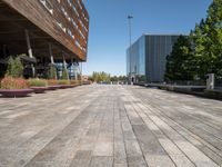 an empty brick walkway leads to an office building and trees in the background for a caption