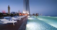 this hotel pool is full of pools and lounge chairs and chairs are lit up at night