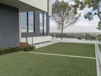 large artificial grass lawn with wooden railings and a modern house on the horizon below