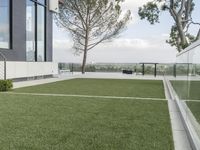 large artificial grass lawn with wooden railings and a modern house on the horizon below