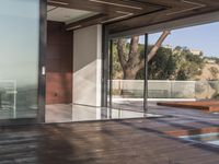 a view out onto the trees of a large modern house in california city, with an outdoor deck with wooden benches and stairs