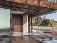 a view out onto the trees of a large modern house in california city, with an outdoor deck with wooden benches and stairs