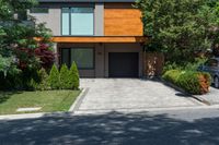 a car parked in front of a big modern house with the driveway visible behind it