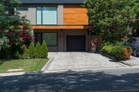 a car parked in front of a big modern house with the driveway visible behind it