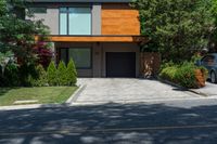 a car parked in front of a big modern house with the driveway visible behind it