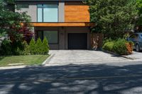 a car parked in front of a big modern house with the driveway visible behind it